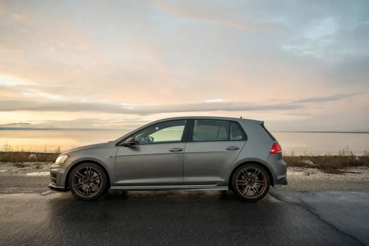 Srebrny VW Golf na nadmorskiej drodze o wschodzie słońca